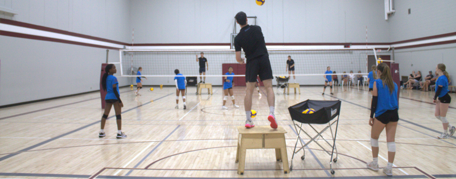 Coach leading a volleyball clinic with youth athletes in AIRTIME jerseys